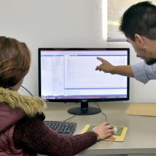 Profesor y estudiante frente a una computadora