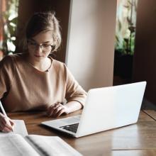 Estudiante frente a computadora, tomando notas