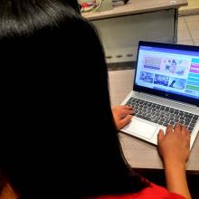 Mujer frente a la computadora con página de UDGVirtual