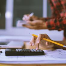 personas trabajando en escritorio con calculadora y libreta