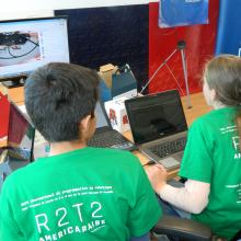 Niños trabajando frente a computadora de escritorio, en el proyecto R2T2