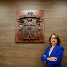 Rectora Maria Esther Avelar, delante del logo de la Universidad de Guadalajara
